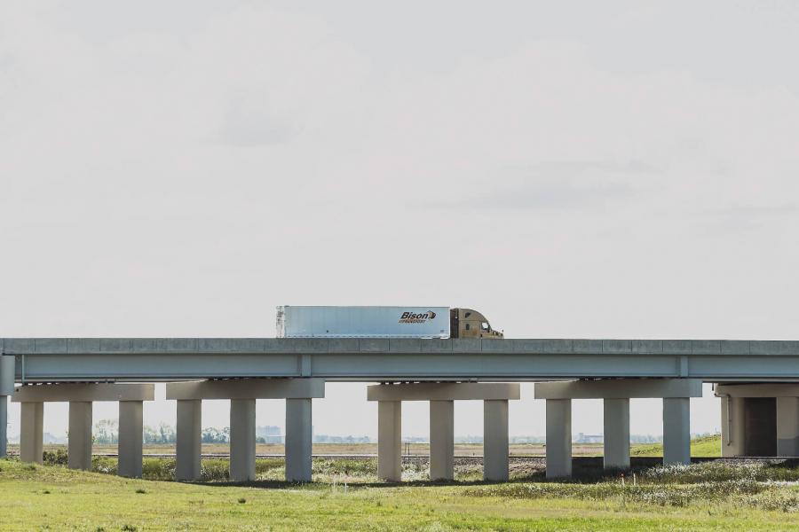 A Bison Transport truck crosses over a highway overpass.