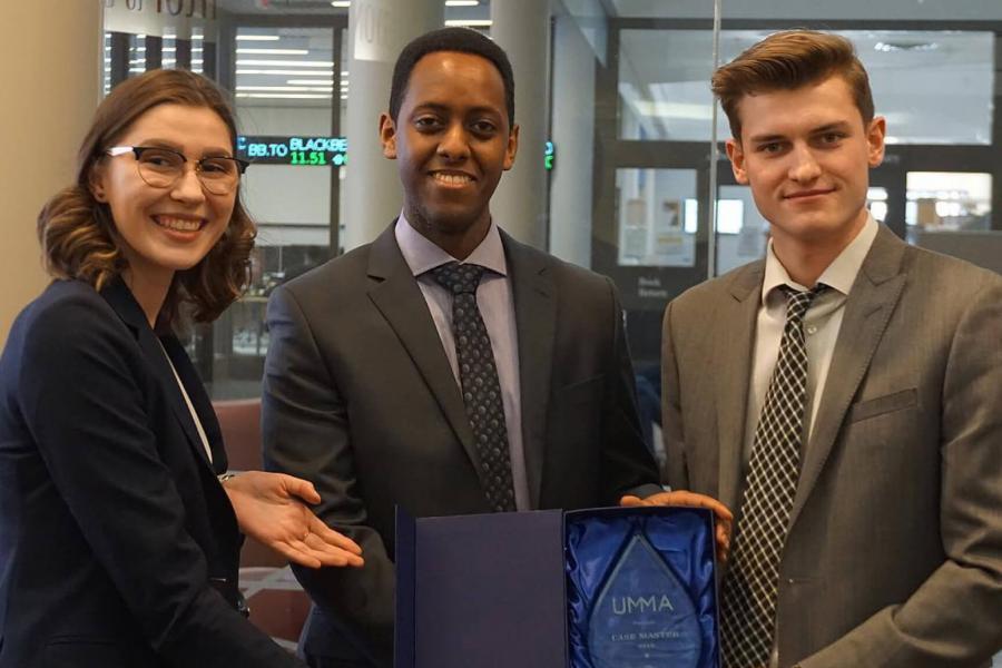 Members of the University of Manitoba Marketing Association pose for a photo together holding an award. 