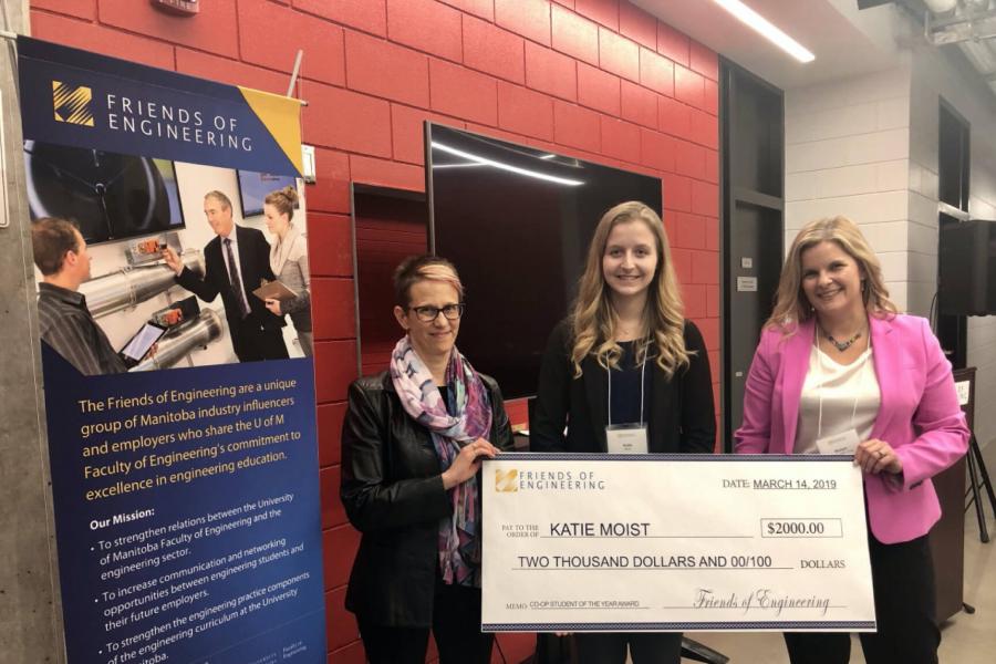 A civil engineering student poses for a photo with a giant cheque she received as an award.