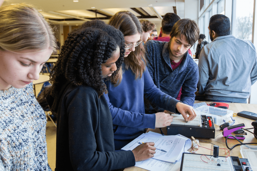 A group of engineering students work together on a project in a classroom.