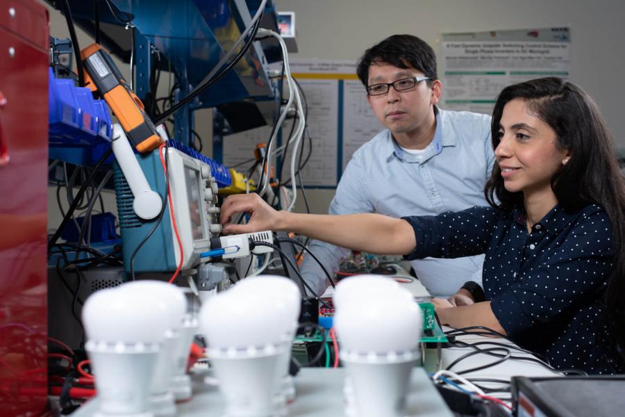 An engineering researcher works with a student in a lab.