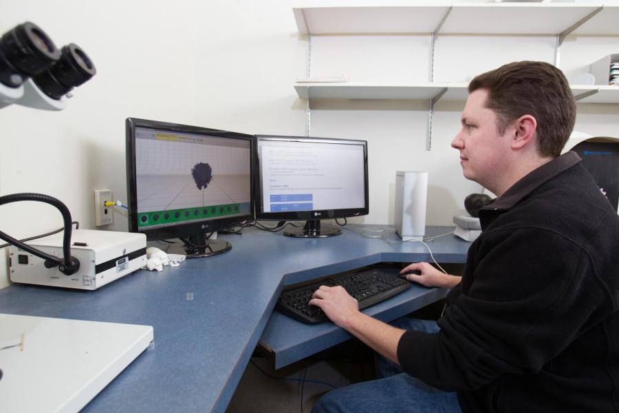 A student works at a computer work station in a lab.