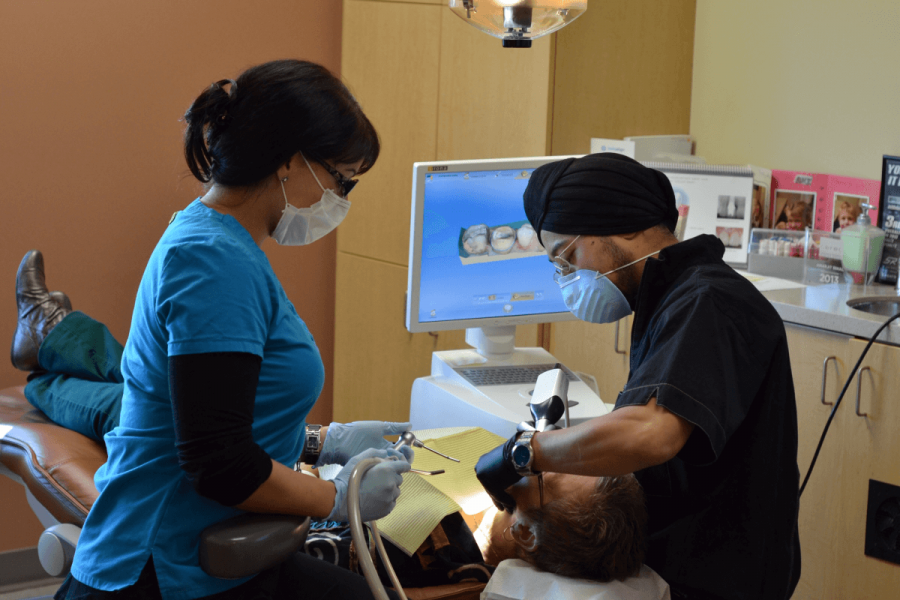 Two dentists work with a patient.