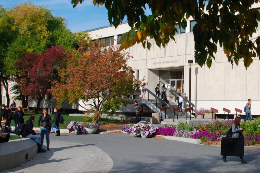 The exterior of the education building with several students walking around outdoors.