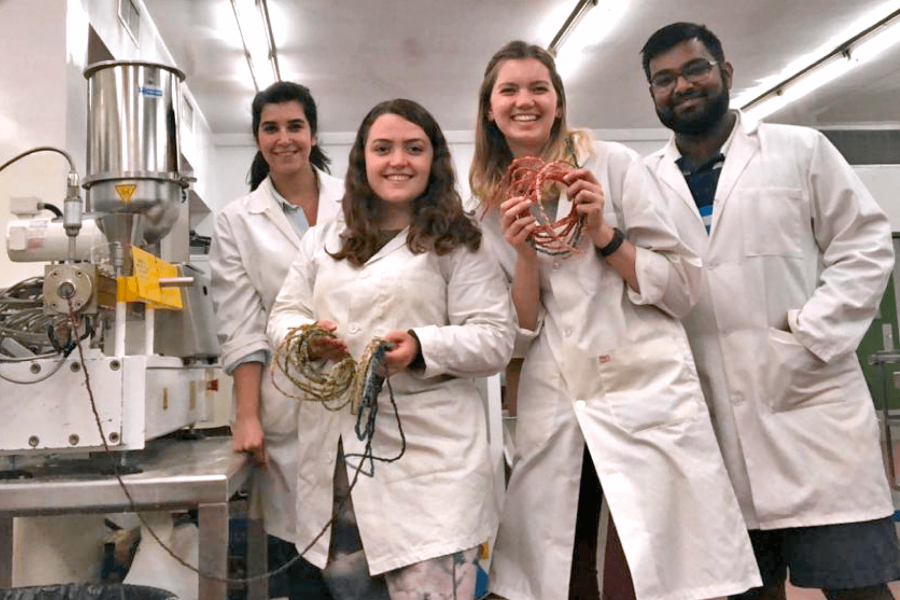 Four food sciences students stand side by side holding protein snacks they have created.