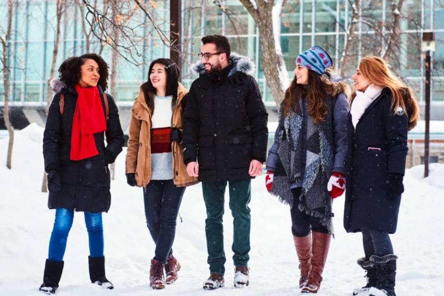 A group of five international students walk outdoors together.