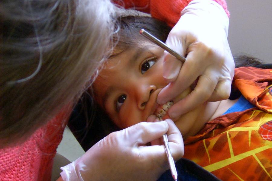 A dentist inspects a young patients teeth.