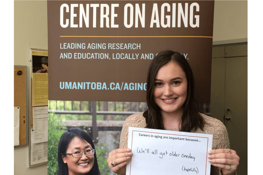 A Centre on Aging student stands with a sign which says 'Careers in aging are important because we all get older'.