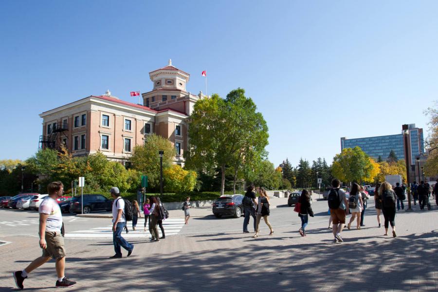 People walking outdoors in front of the Administration building at the University of Manitoba Fort Garry campus.