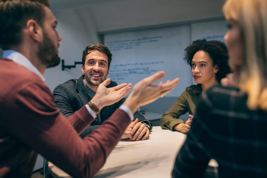 A small group of adults gathered around a table having a meeting.