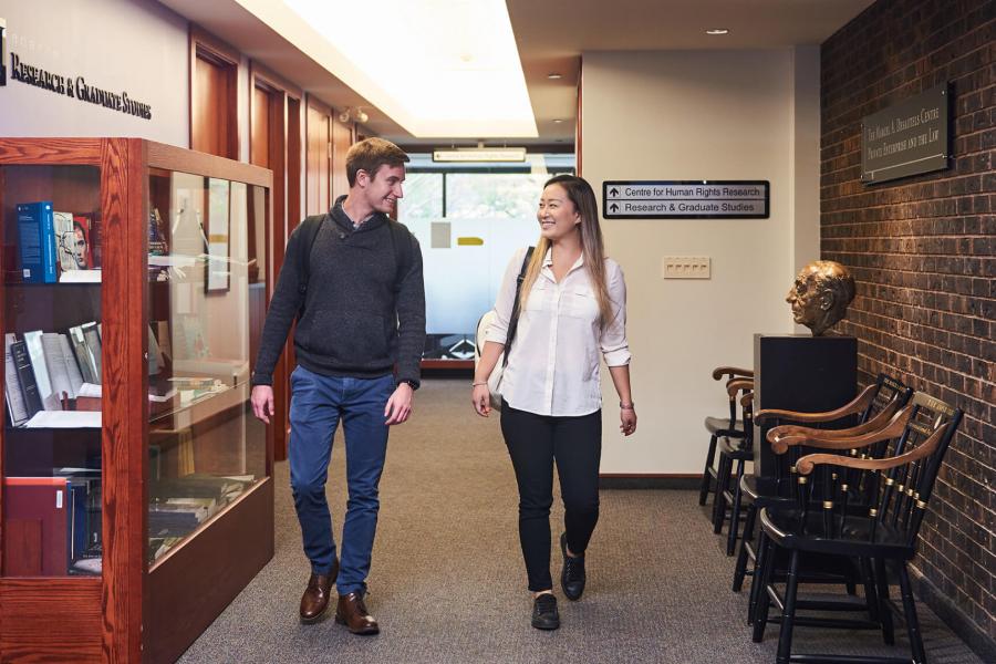 Two students walk together down a hallway.