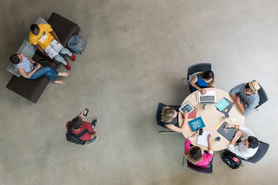 An aerial view of students seated at a table and a small bench studying.
