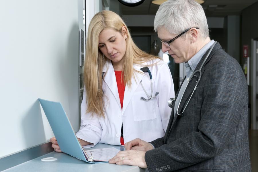 A medicine student and an instructor look down at an open binder 