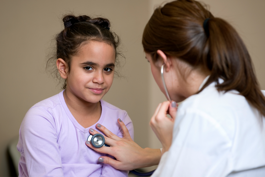 A Physician holds a stethoscope to a child's chest.