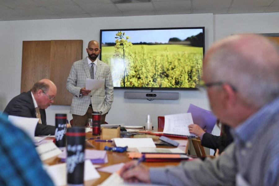 A man stands and speaks in a boardroom.