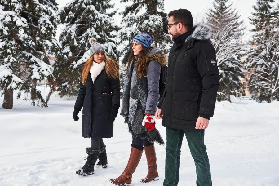 Three International students walk together outside on the University of Manitoba campus in winter.