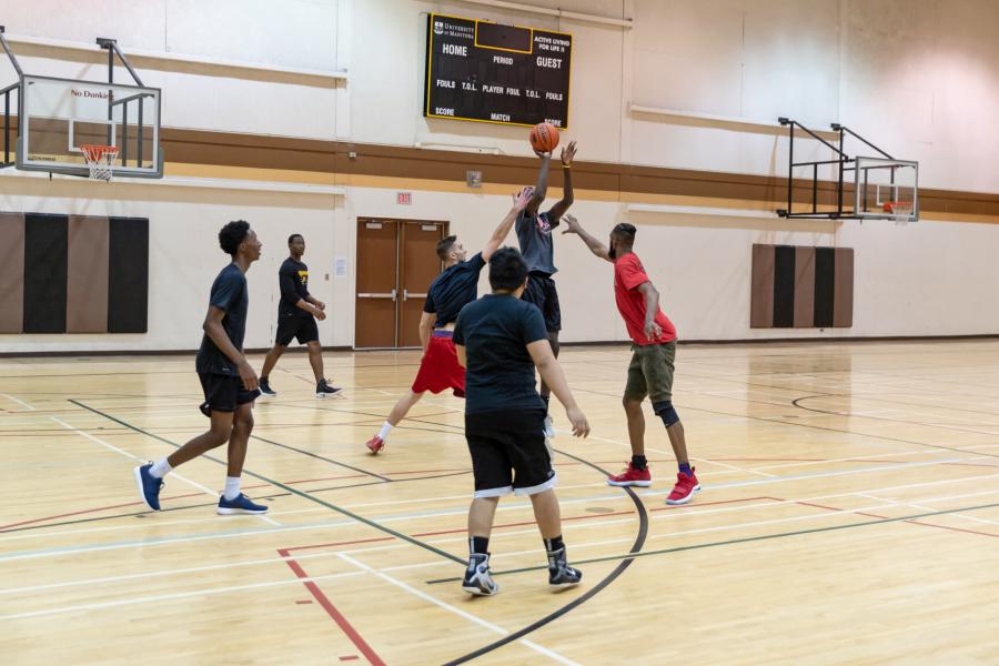 A group of six students playing a recreational basketball game on the Frank Kennedy Centre gymnasium basketball court.