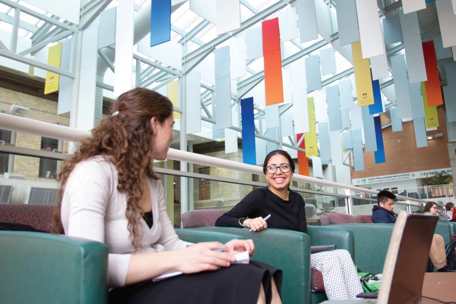 Two students sitting together in the University of Manitoba Bannatyne campus Buhler atrium