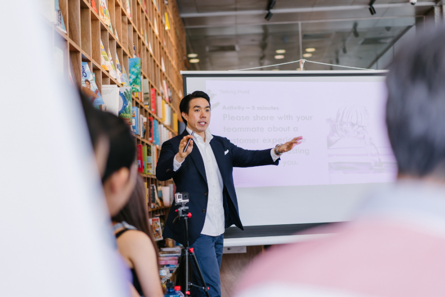 Man in front of screen giving presentation. 