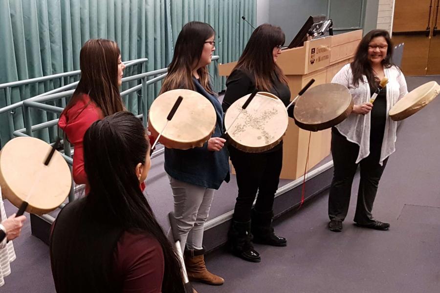 Musicians drumming on Indigenous drums.