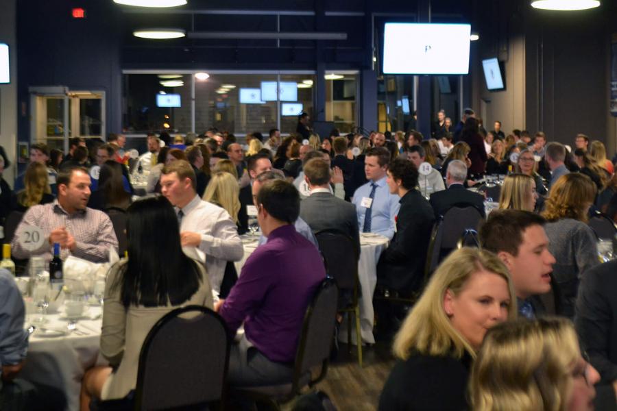 Students and employers in business attire are seated at banquet tables.