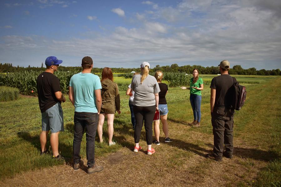 Students and instructor stand in a field.