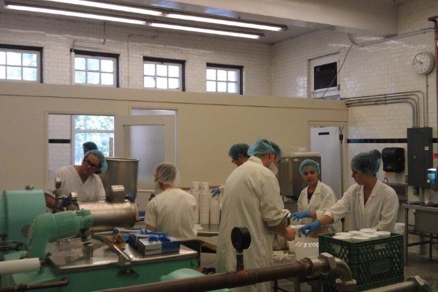Students in lab coats and hair nets work in a food lab.