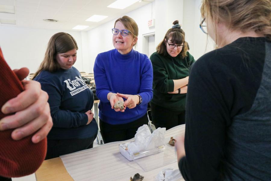 Photo of professor Lea Stirling showing artifacts to students.