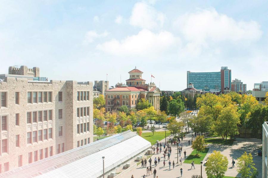 The Fort Garry campus with many trees and pedestrians from a rooftop perspective. In the foreground is a large traditional brick limestone building with attached greenhouse. In the middle distance is a red brick building with Canadian flag and a modern glass apartment building. 