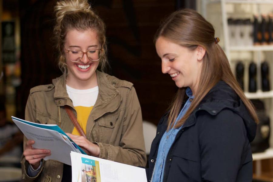 Two smiling students read orientation materials.