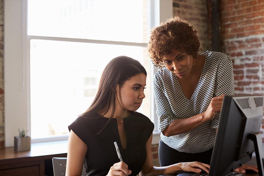 Two business women working on a computer in the office.