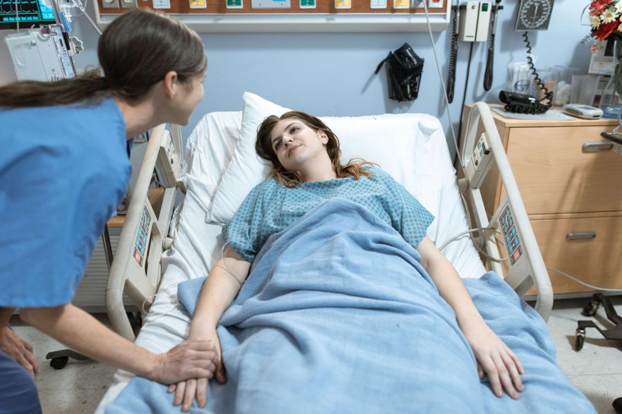 Nurse holding the hand of a patient in bed.