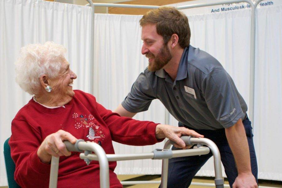 A physical therapy student talking to an elderly woman.