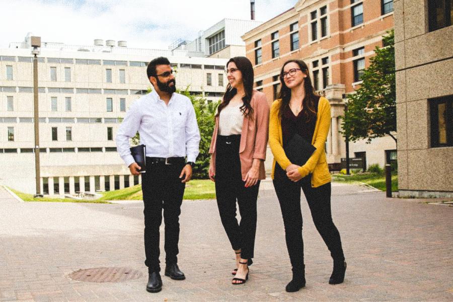 An image of three people standing outside on UM's Fort Garry campus, smiling and conversing.