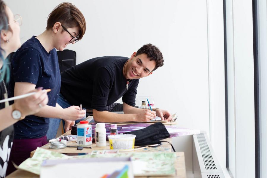 Three students are painting in a bright white ARTlab classroom.