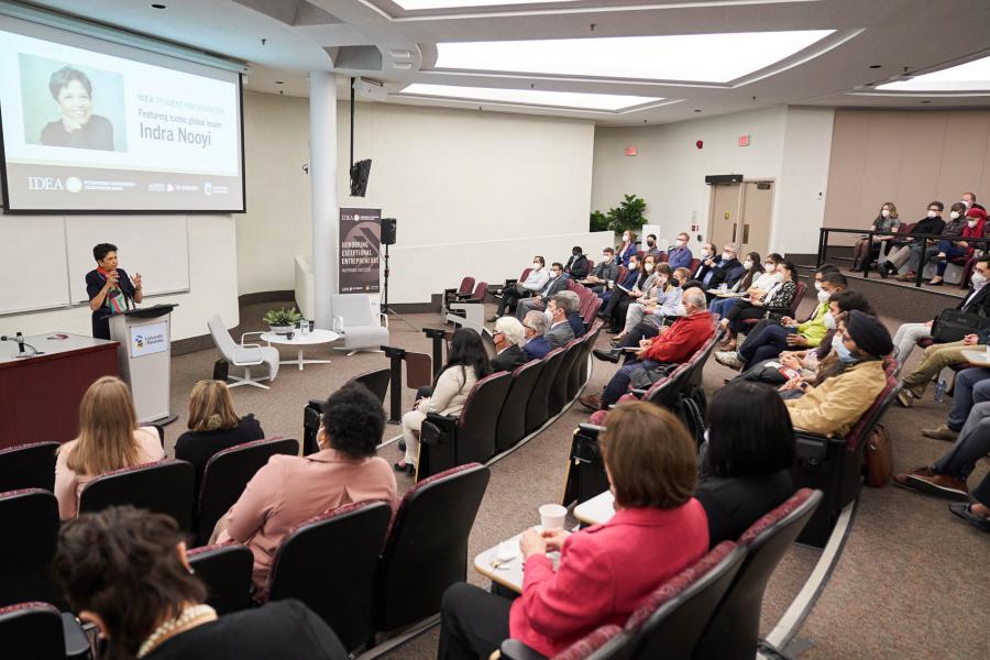 A full lecture hall of people are seated in a Drake Centre lecture hall facing speaker and business leader Indra Nooyi.