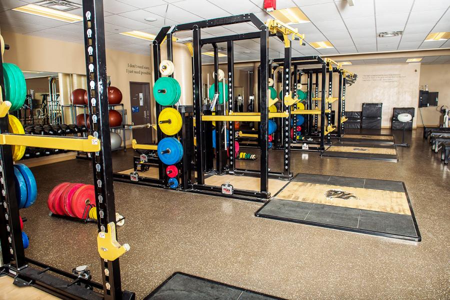 A weight room at IG Field shows rows of different coloured barbell weights and other work out equipment.
