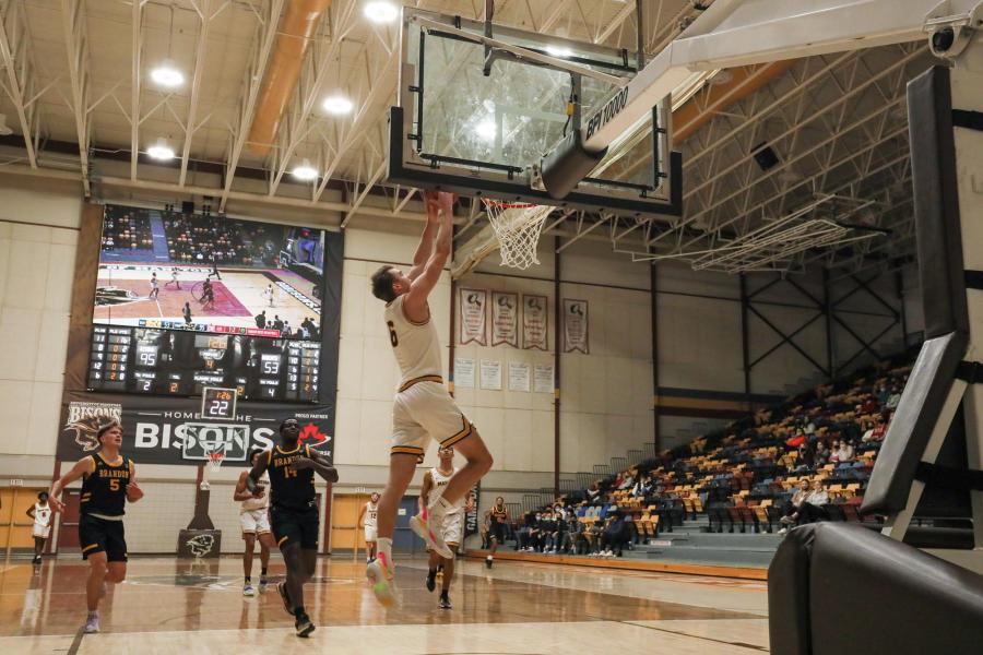 A University of Manitoba Bisons basketball player dunks the ball into the net at a game inside the Investors Group Athletic Centre.