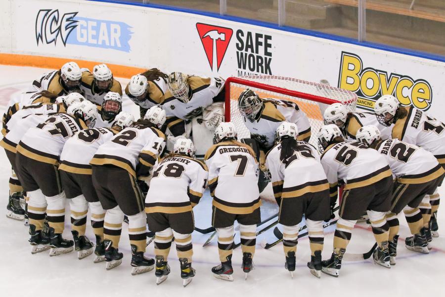 University of Manitoba Bisons hockey players huddle on the ice near the goalie net on the ice at the Max Bell Centre.
