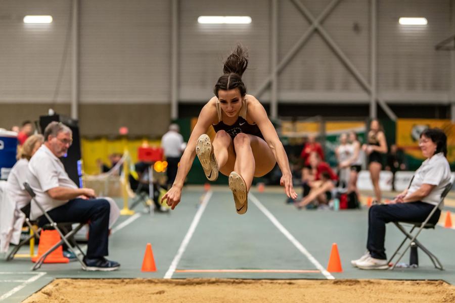 An athlete in the air seconds before landing in the sand pit during a long jump event at the Max Bell Centre.