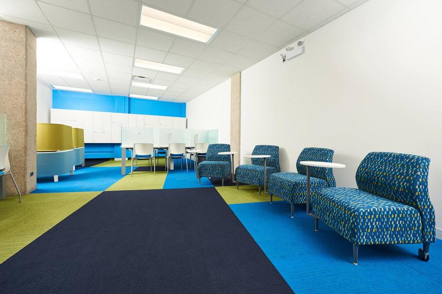 A room in the Faculty of Law Robson Hall with a bright square patterned blue and green carpet and patterned couches.