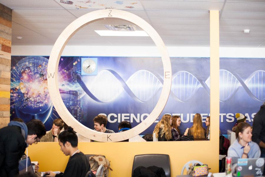 Students sit at tables in the lounge area of the Science Complex building's Science Students Association area.