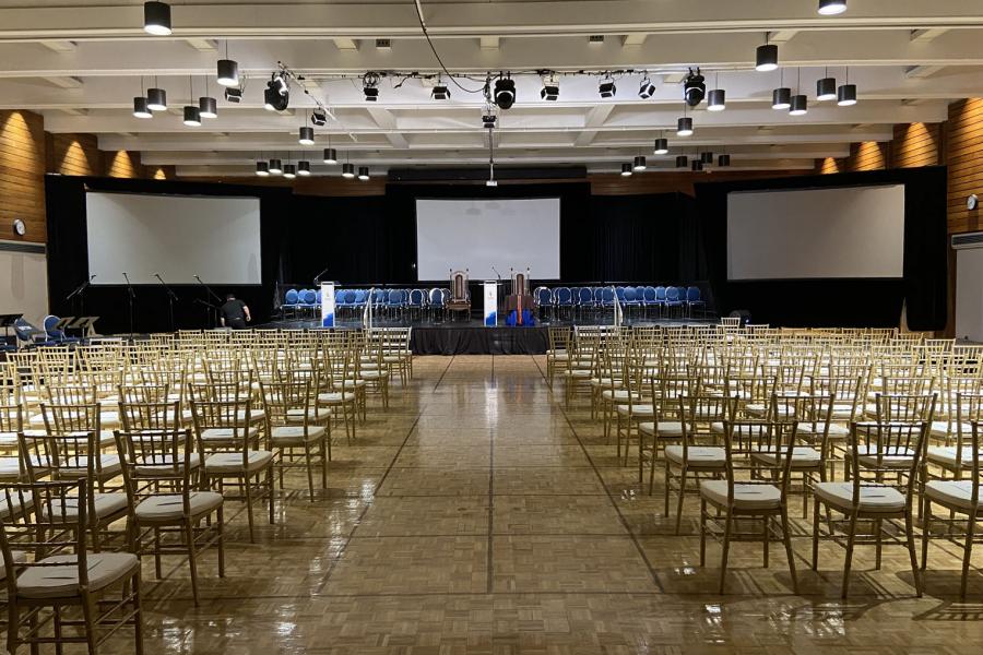 Rows of gold and white chairs in rows face a stage in a multipurpose room staged for a graduation ceremony at the UMSU University Centre.