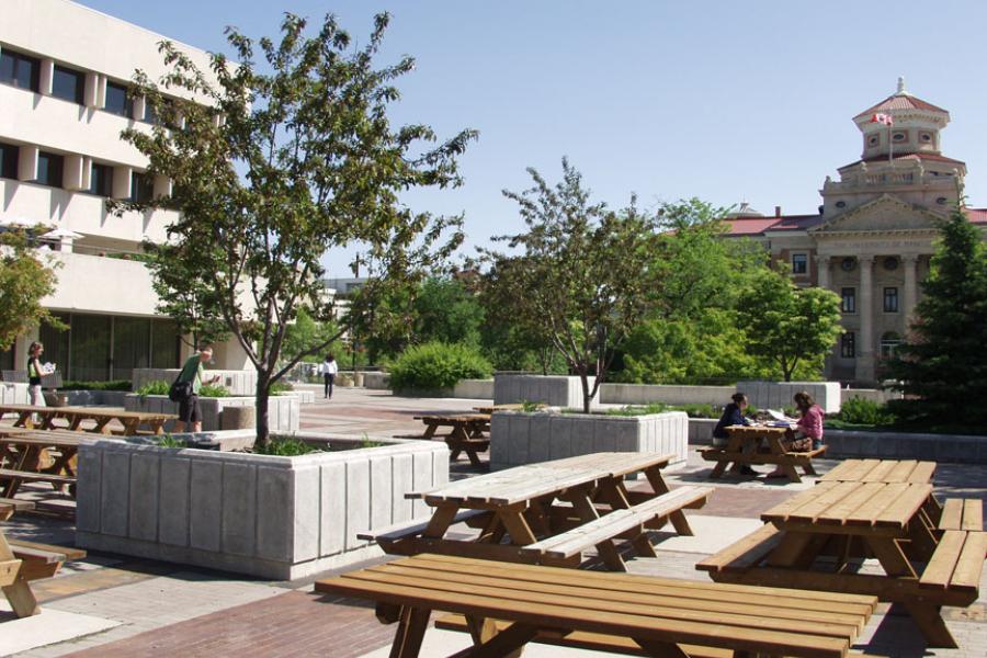 A view from the second floor outside dining area with picnic benches on a sunny day outside of the UMSU University Centre.