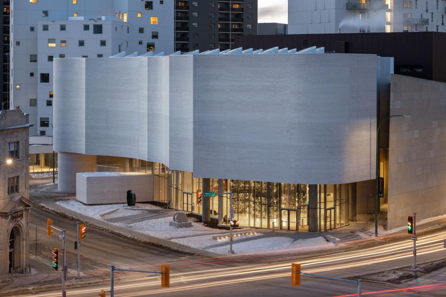 Modern, white WAG– Qaumajuq building at dusk, light snow on the ground