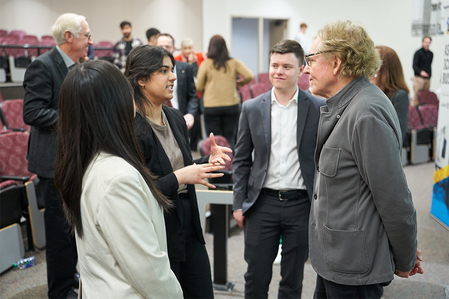 Three Asper students talking to a presenter in a classroom.