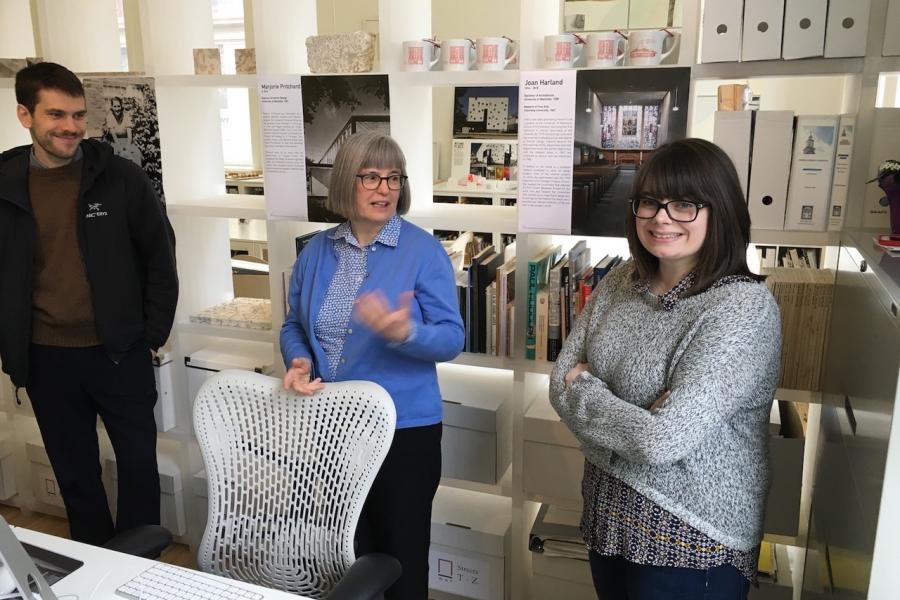 Three guests posing in front of student designs at a Architecture Foundation exhibition.