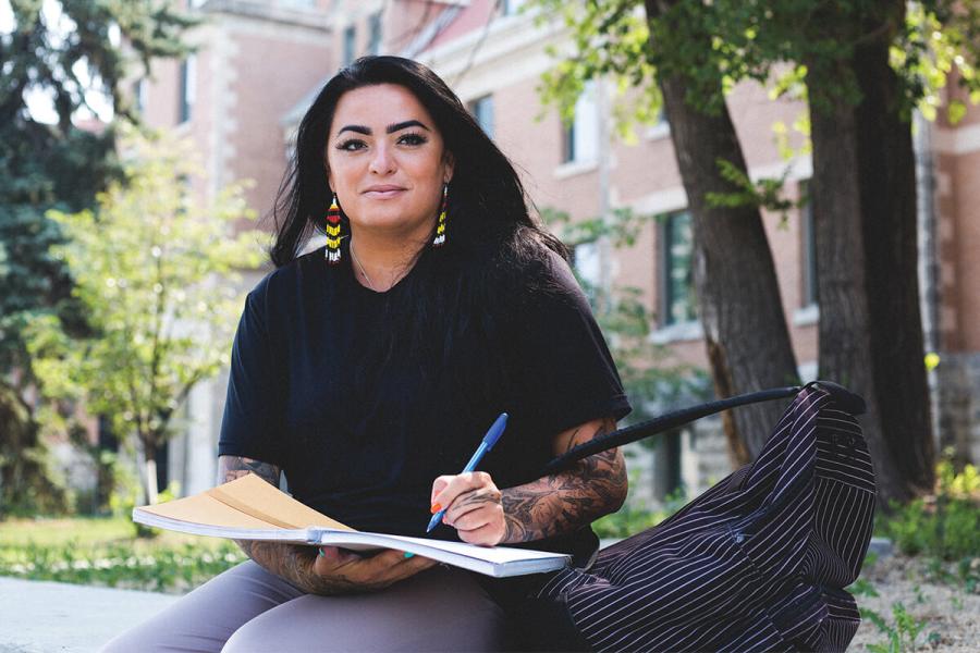 An Indigenous student studying under in the open space on campus. 