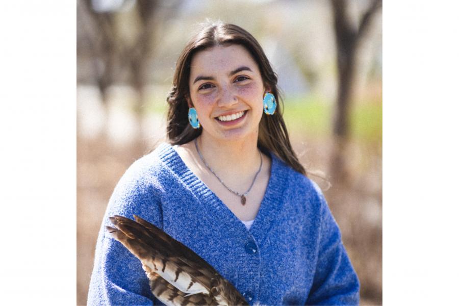 Image of an female Indigenous student smiling with a feather. 