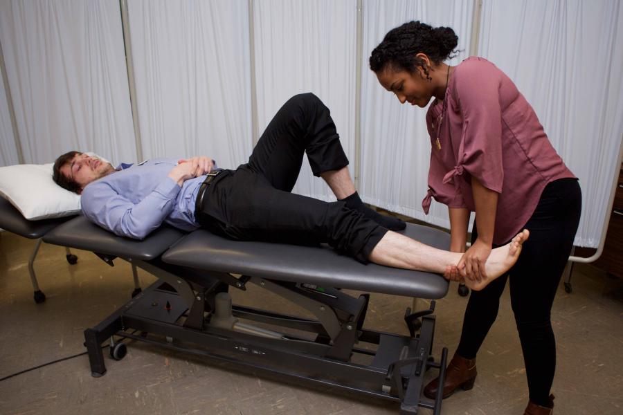 A physical therapy student stretching a patients leg.